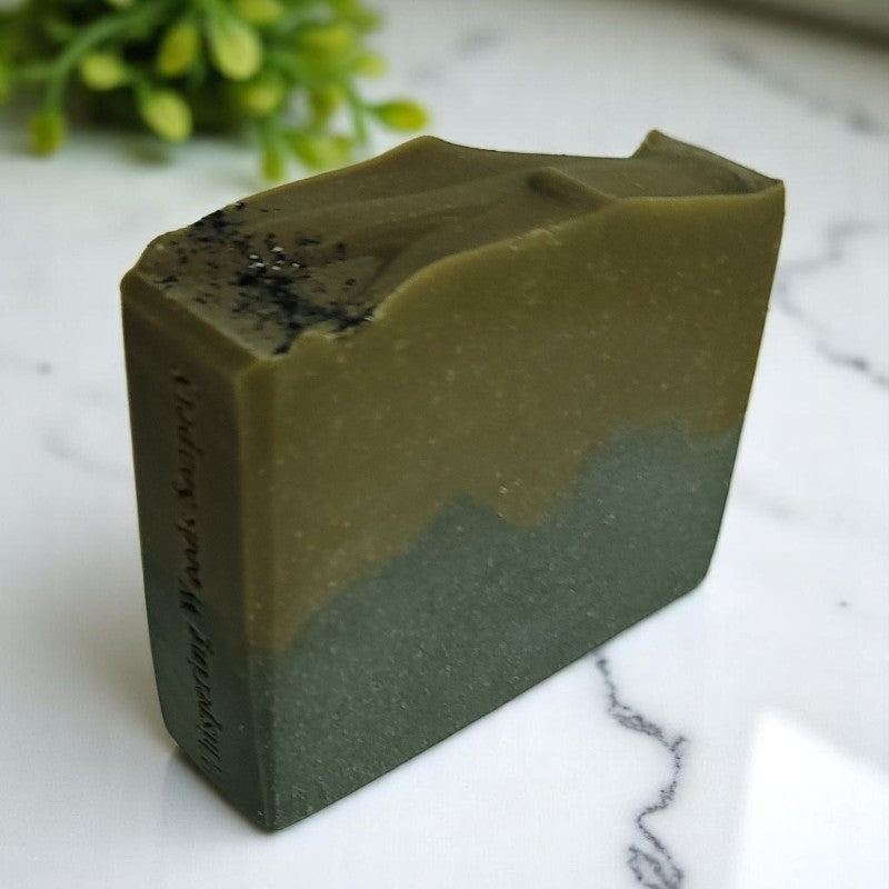 A greenish-brown and black bar of soap on a marble counter