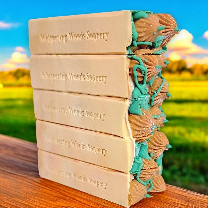 A side view of a stack of five bars of soap with piped orange pumpkins and green leaves/vines on top