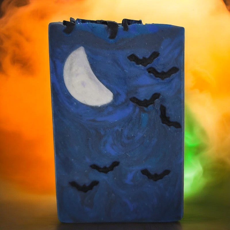 A blue bar of soap with seven small bats and a crescent moon embed with orange and green fog behind it