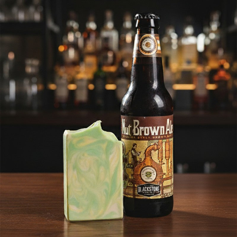 Bottle of Blackstone Nut Brown Ale with a bar soap on a wooden surface, blurred bar background