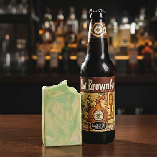 Bottle of Blackstone Nut Brown Ale with a bar soap on a wooden surface, blurred bar background