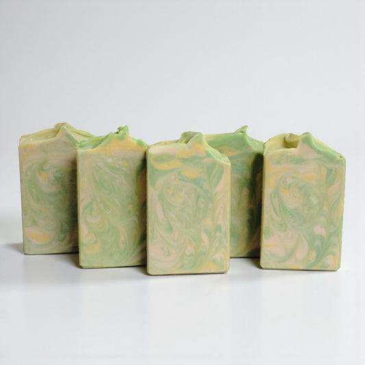 Five tan, yellow and green swirled soap bars on a white background