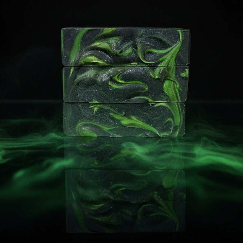 Three green and black marbled soap bars on a reflective surface with a dark background and green fog