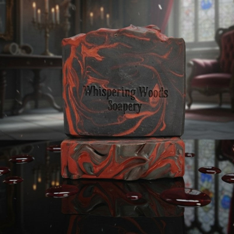 Two red and black swirled soap bars on a black shiny surface with drops of blood