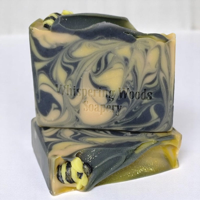 Two bars of soap with yellow, gold and black swirls that have tiny soap bees on top