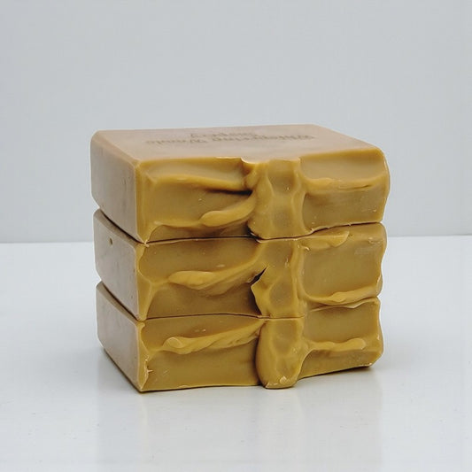 Stack of three gold-brown soap bars on a white background