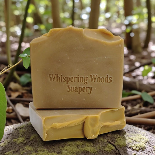 Bars of soap with 'Whispering Woods Soapery' branding on a natural background