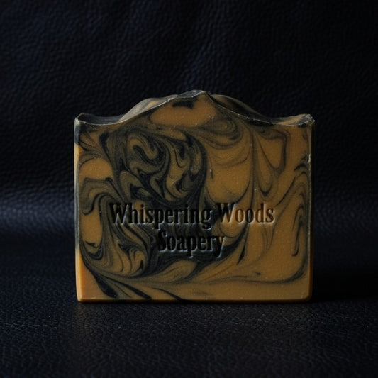 An orange and black swirled soap bar on a black leather background
