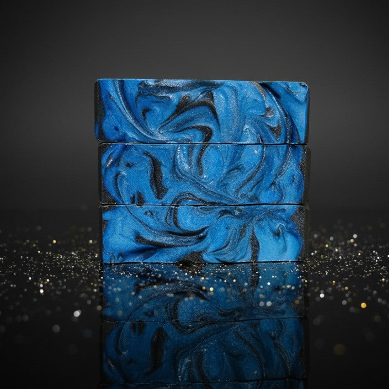 A stack of blue and black swirled soaps on a black reflective surface