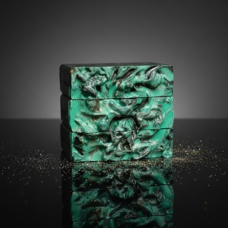 A black and green swirled stack of soaps on a black reflective surface