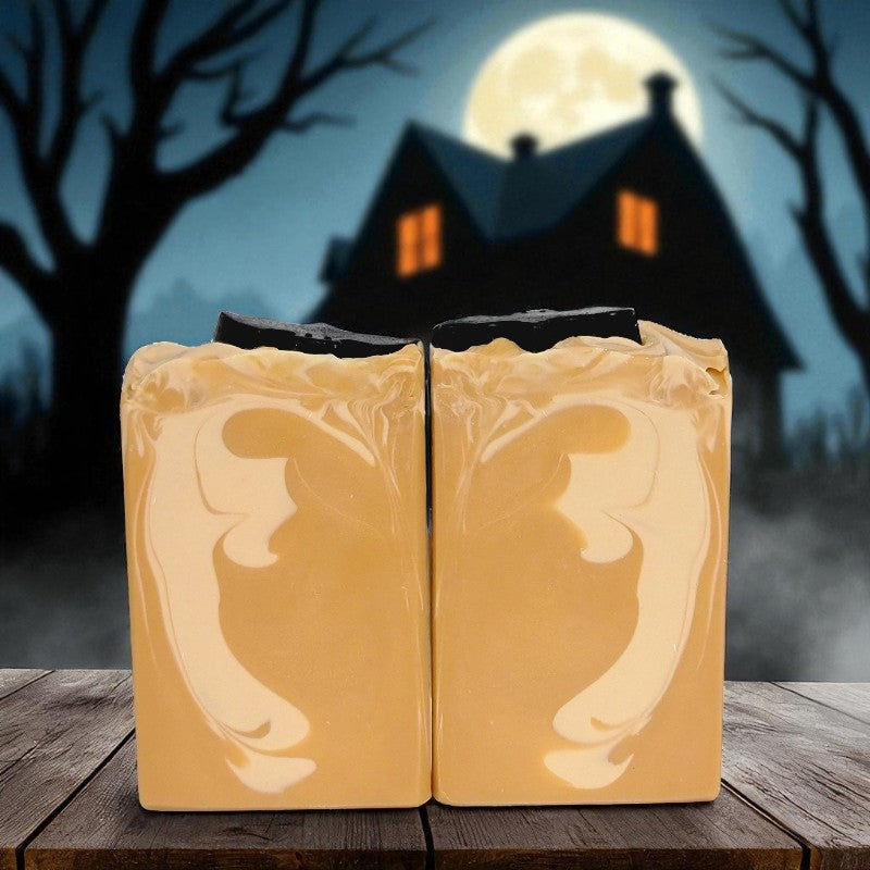 Two bars of orange soap with a haunted house and full moon in the background