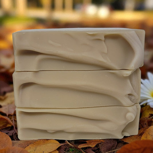 Stack of beige soap bars on a natural background with leaves and a flower