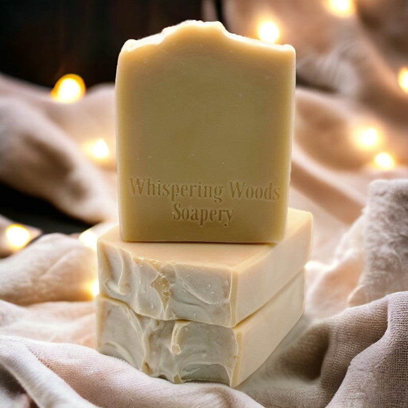 Three bars of yellowish-tan soap on linens with soft lights in the background