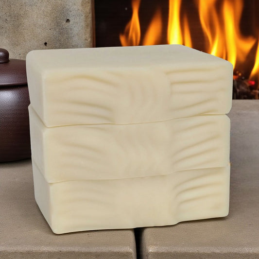 Three stacked cream soap bars with a fireplace in the background