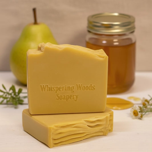 Two golden-colored bars of soap with a pear and jar of honey