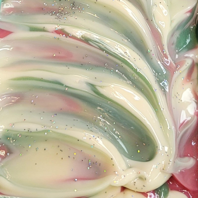 Close-up of wet freshly-poured soap with swirls of pink, green and white and glitter topping