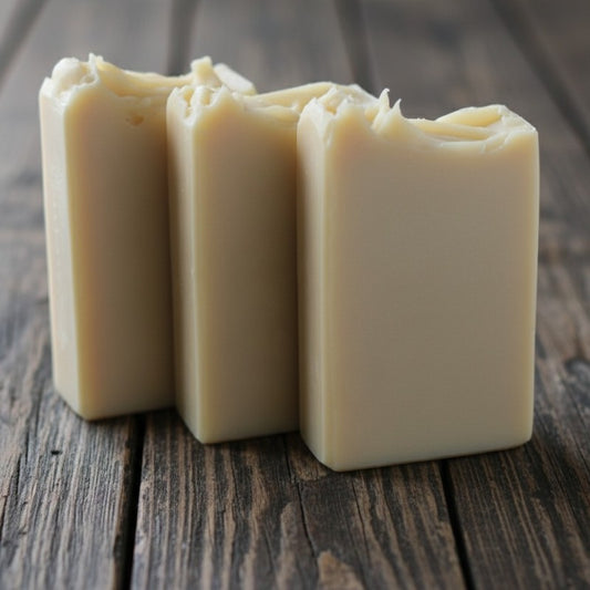 Three bars of cream colored soap on a wooden surface