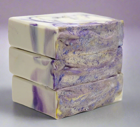 Three bars of soap with a purple and white swirled pattern on a light purple background