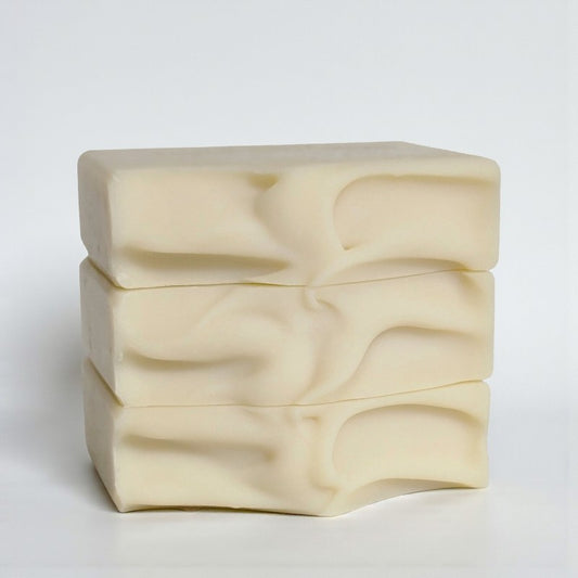Cream-colored bars of soap stacked on a white surface