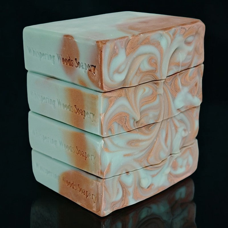 Four bluish-green and copper swirled soap bars stacked on top of each other on a plain black background