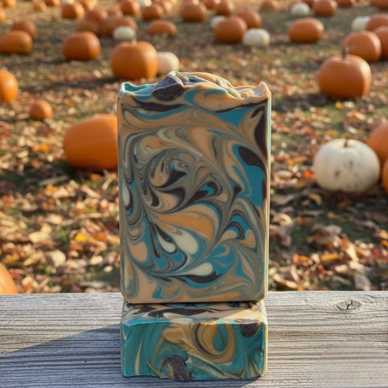 Marbled soap bar in teal, brown, orange and champagne colors with pumpkins in the background