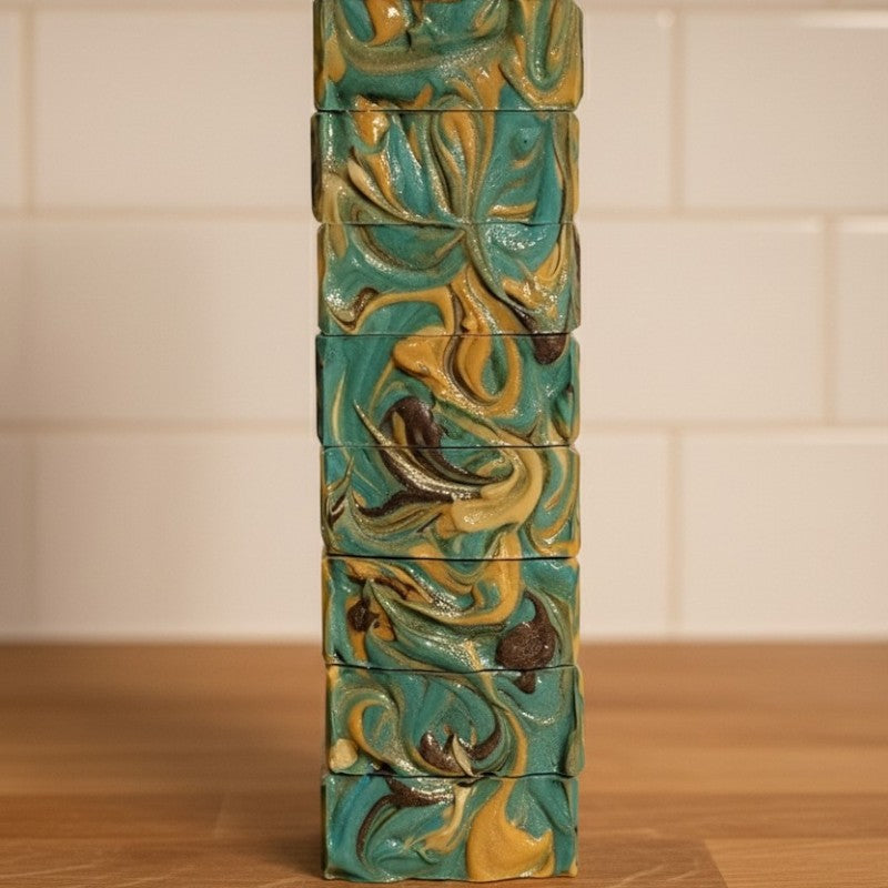 Stack of soaps with textured tops on a wooden counter with white tile in the background