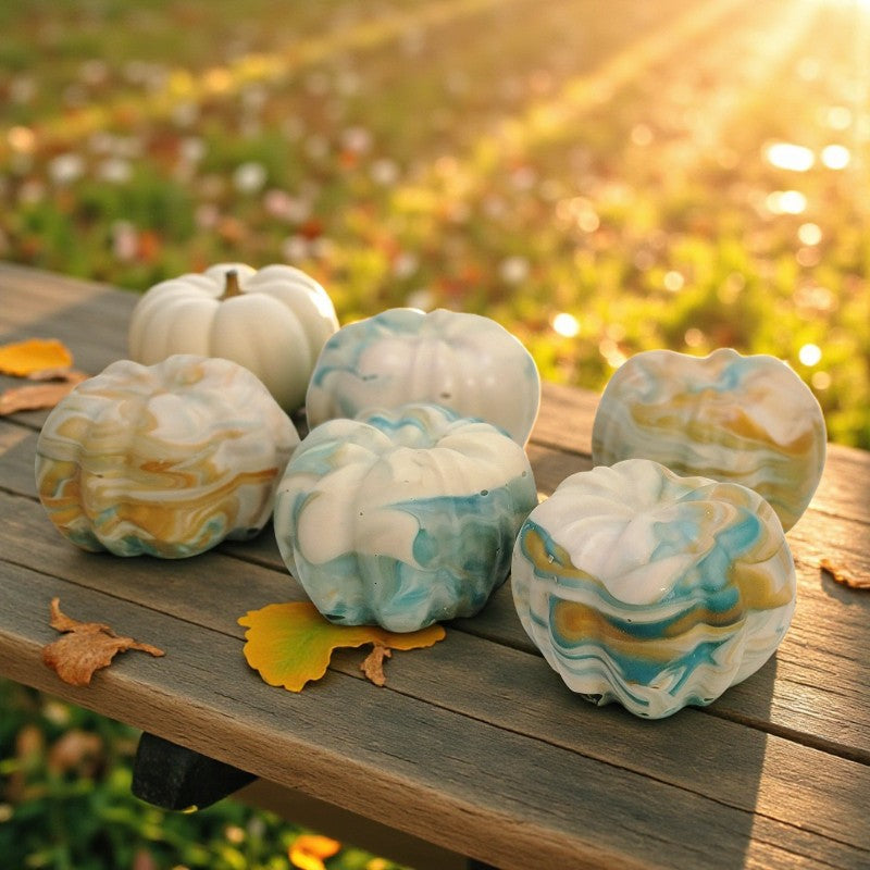 Marble-patterned pumpkin soaps on a wooden surface with a blurred natural background