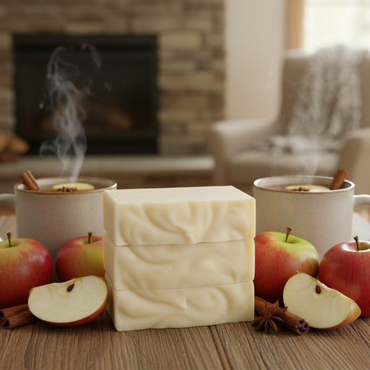 Three cream colored bars stacked on a table with apples and cider