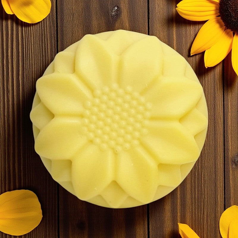 Yellow sunflower-shaped soap on a wooden surface with sunflower petals and a sunflower