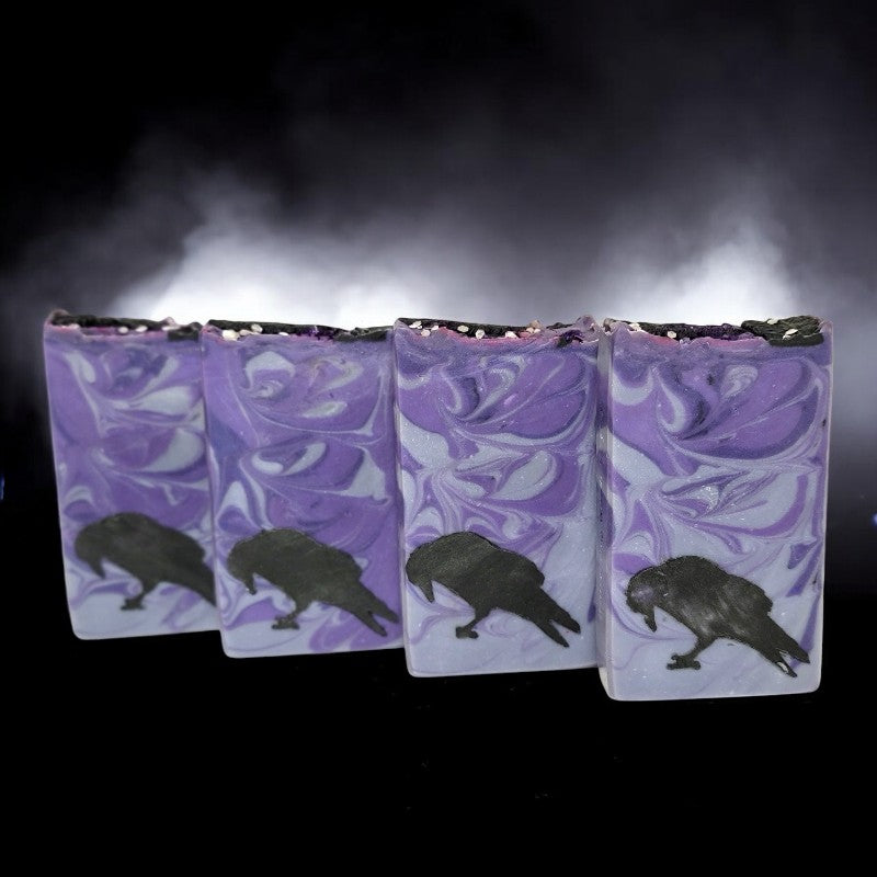 Four bars in a row of purple and silver swirled soap with black ravens toward the bottom edges