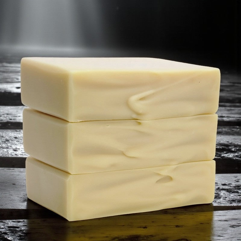 Three stacked bars of soap on a dark wooden surface