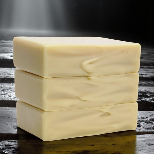 Three stacked bars of soap on a dark wooden surface