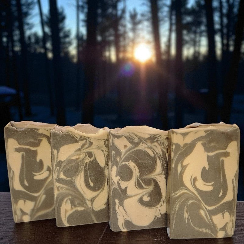 Marbled soap bars on a wooden surface with a forest background