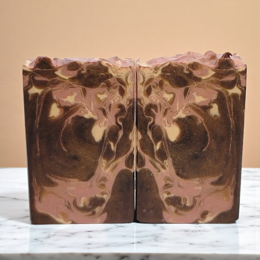 Marbled brown cream and pink soap bar on a countertop with a beige background