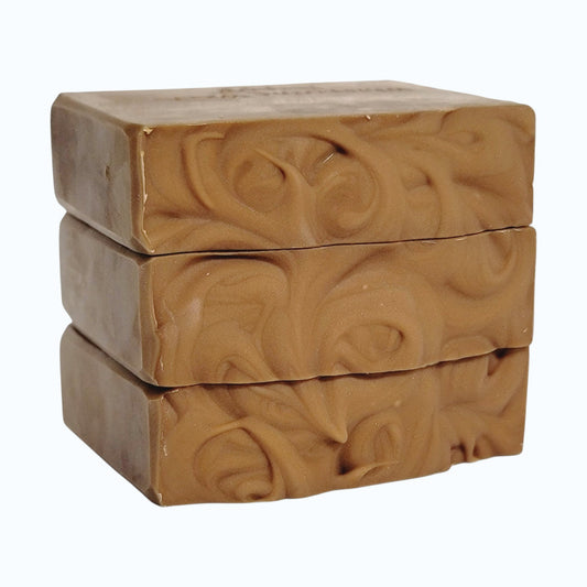 A soap stack showing the textured tops of light brown bars on a white background