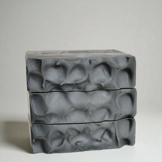 Three bars of silvery gray soap with textured tops on a light gray background