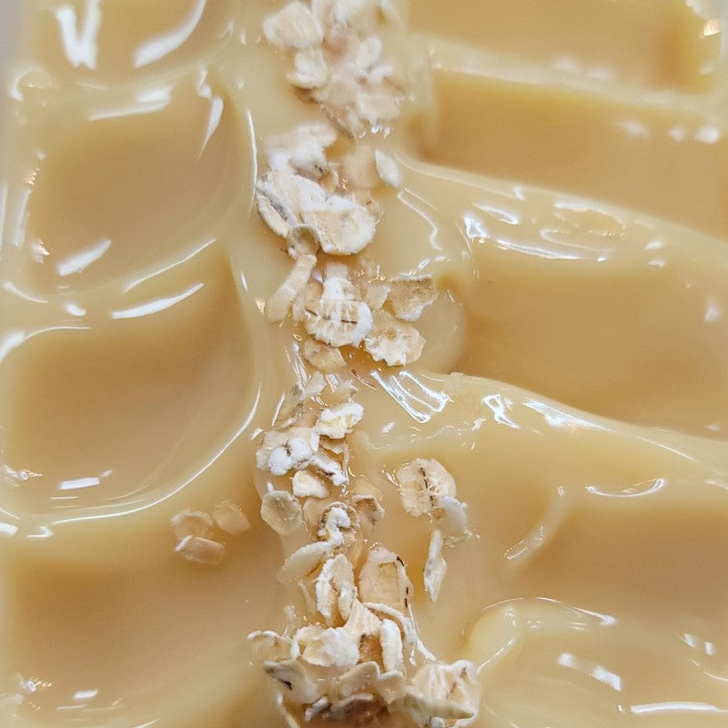 Extreme close-up of freshly poured dark cream soap with a row of oat flakes on the top