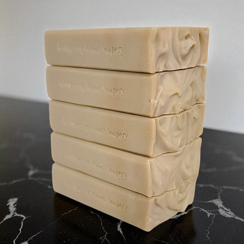 Stack of creamy tan soap bars on a black marble surface with a white background