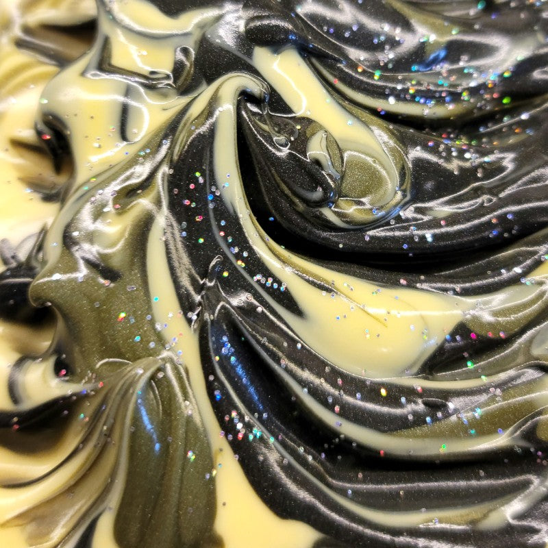 Close-up of freshly poured soap with cream and black swirls along with sparkles on the top