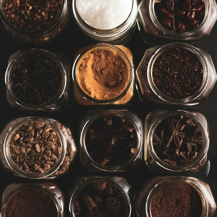 Close-up of the open tops of glass spice jars with various spices