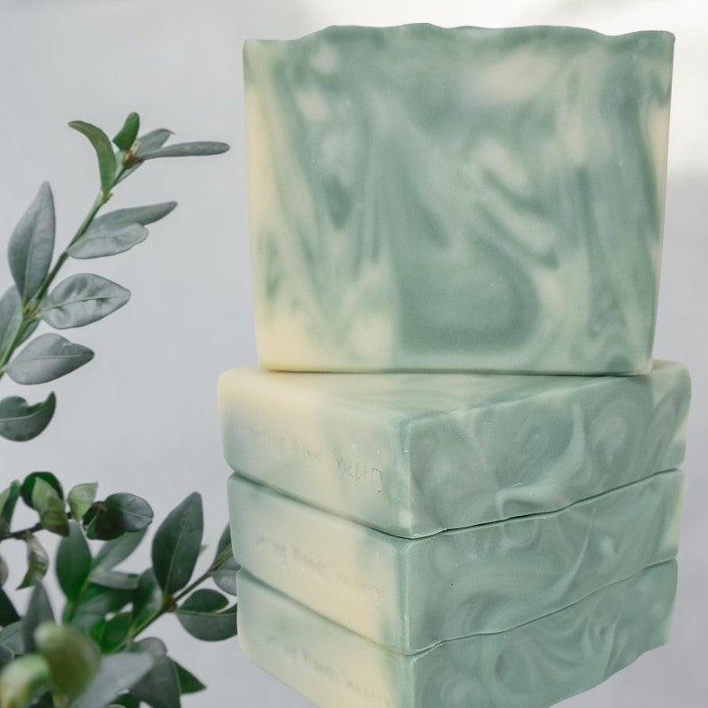 Four bars of creamy white and light green soaps