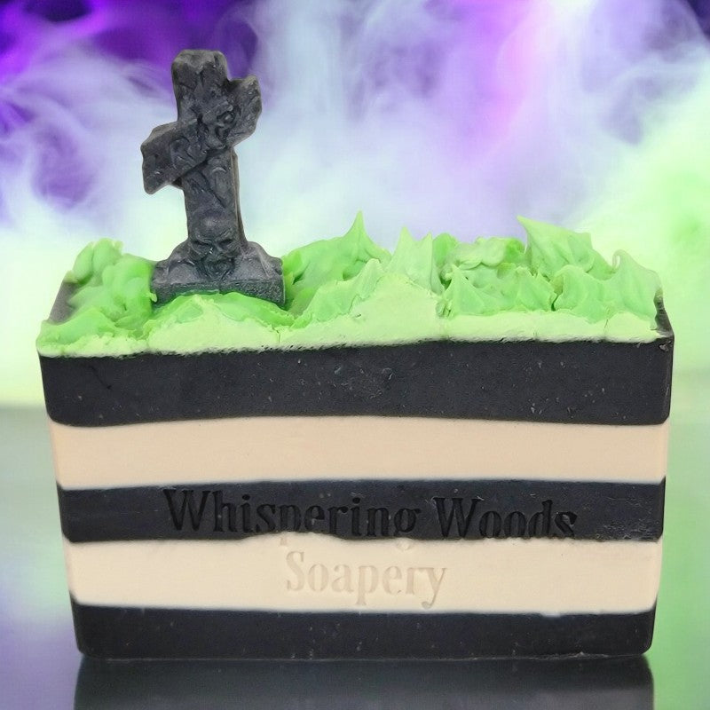 A bar of soap with black and white stripes, topped with neon green grass and a tombstone. There is purple and neon green fog in the background.