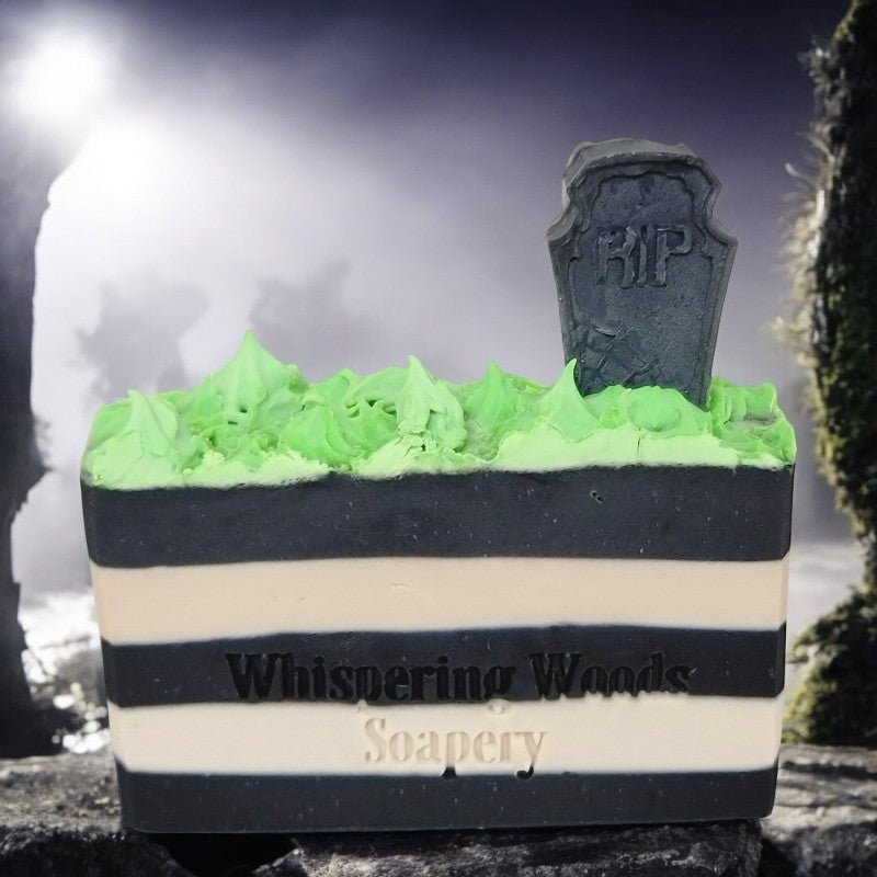 A bar of soap with black and white stripes, topped with neon green grass and a tombstone sitting in a fog-filled cemetery.