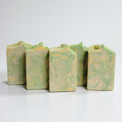Five tan, yellow and green swirled soap bars on a white background