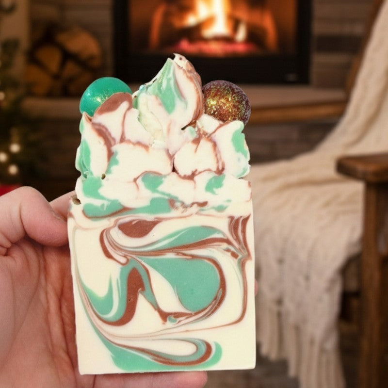 Hand holding a decorative soap bar with a fireplace in the background