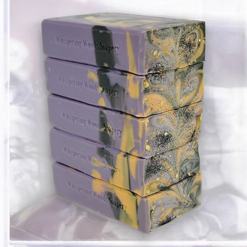 Stack of marbled soap bars with 'Whispering Woods Soapery' branding on a white background