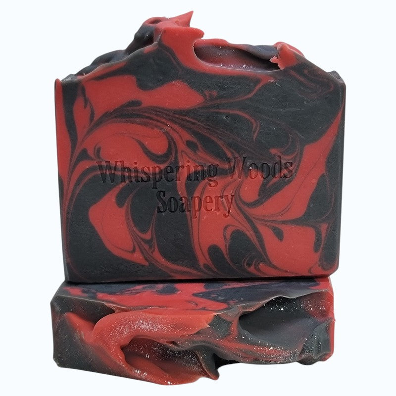 Red and black swirled soap bar with 'Whispering Woods Soapery' branding on a white background