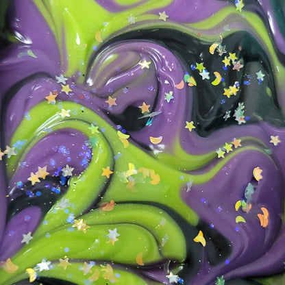 Extreme close-up of freshly poured purple, green and black swirled soap with glitter stars and moons on top