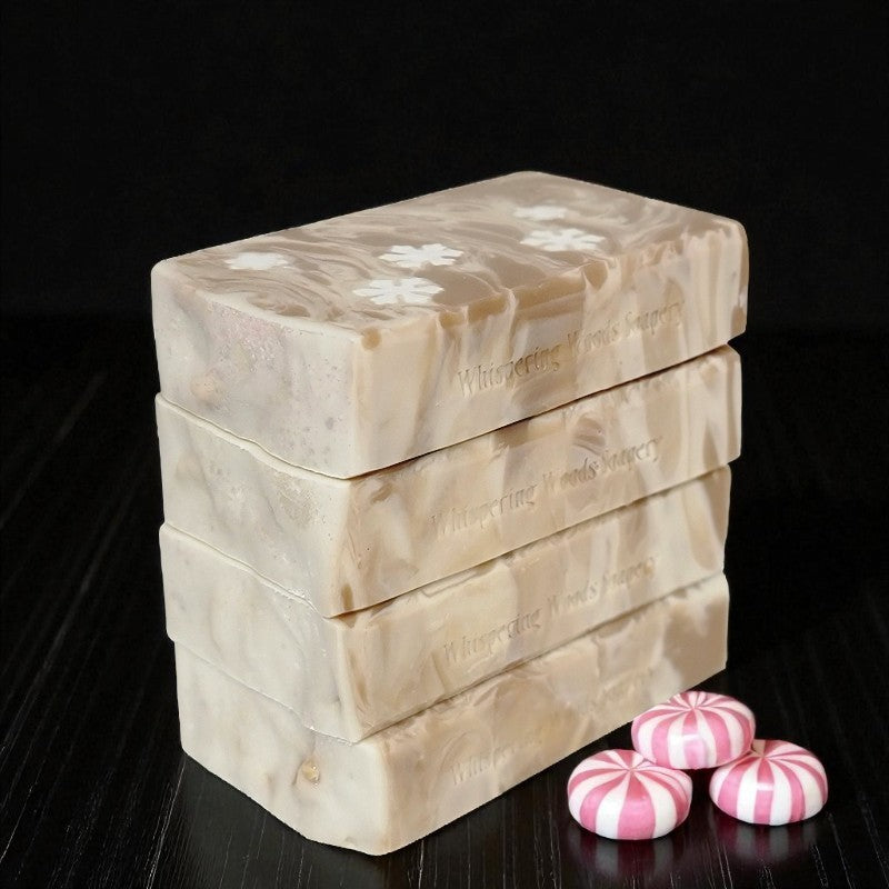 Stack of soap bars with marbled design and 'Whispering Woods' branding, accompanied by pink and white striped candies on a dark background