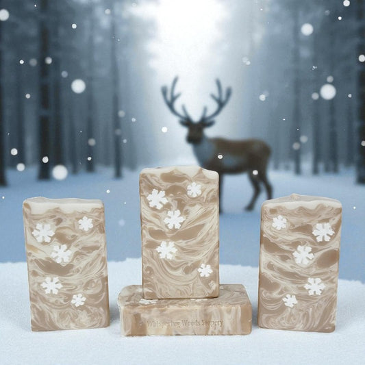 Cream and toffee marble-patterned soap bars with snowflake embeds on a snowy background with a reindeer